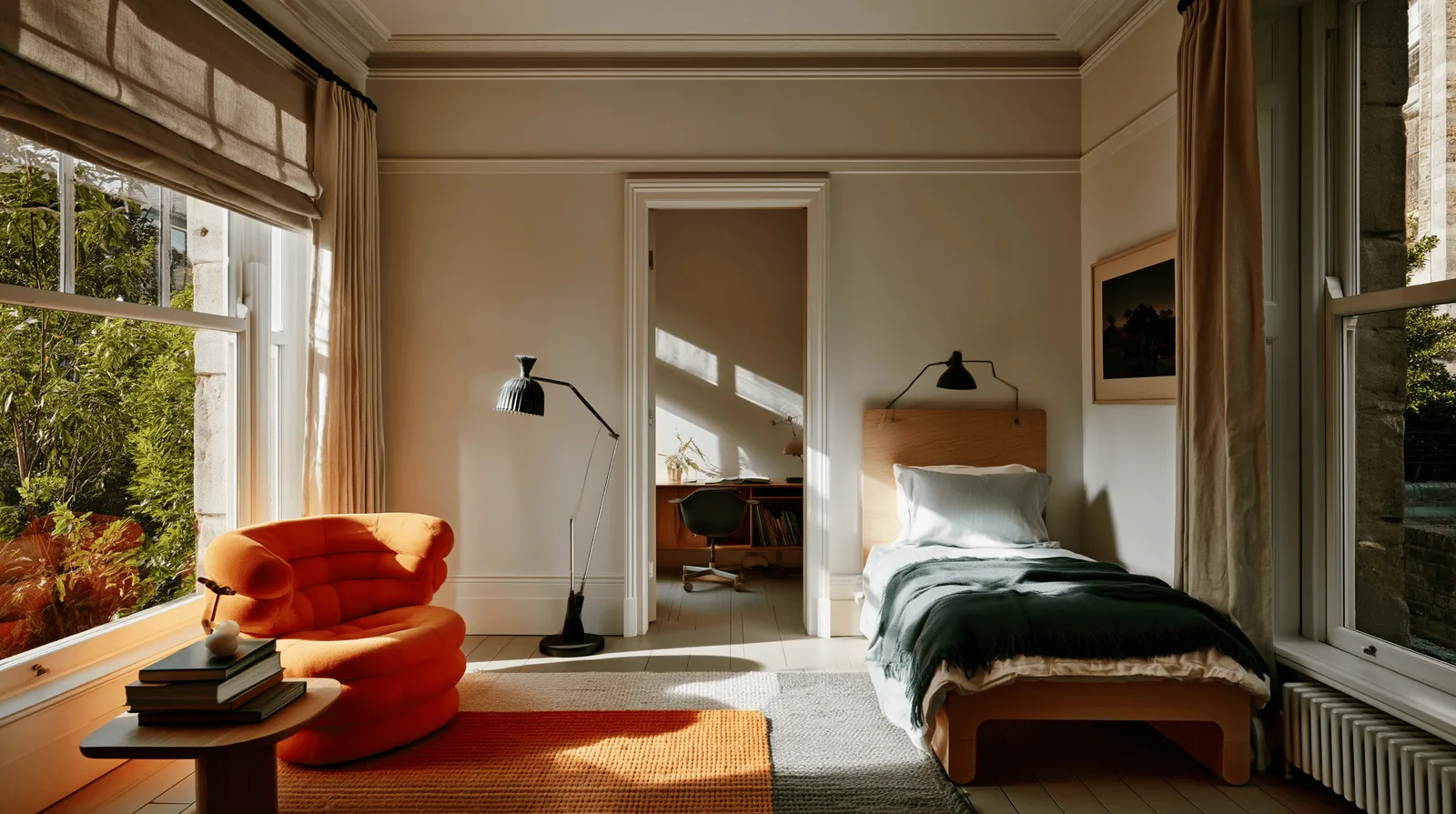 A period room with high ceilings and cornices, an orange armchair in the foreground and a bed beyond